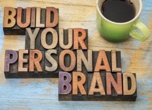" blocks spelling out build your personal brand next to a cup of coffee"